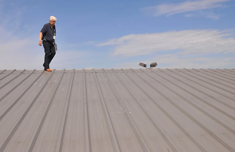 A roofer walking across a standing-seam metal roof