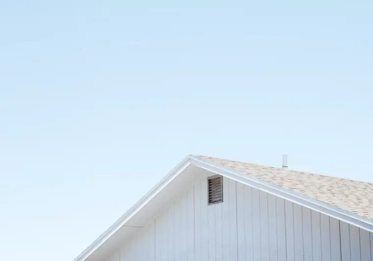 The white gable of a house against a clear sky